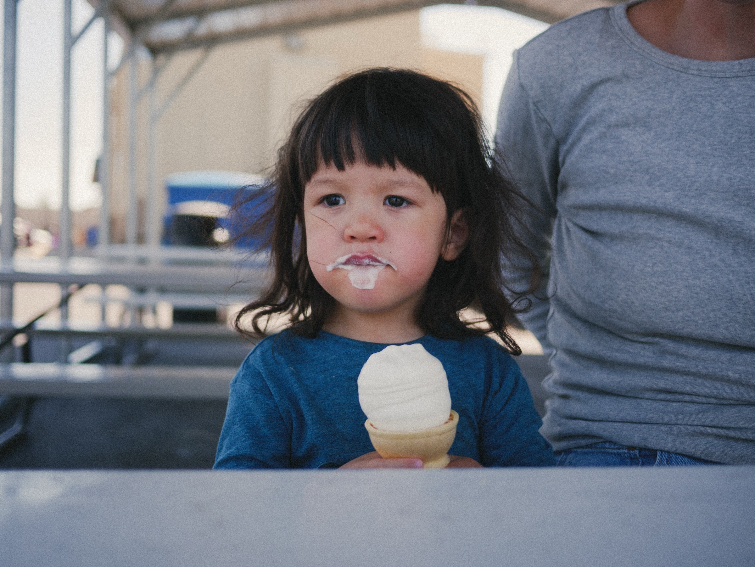 A child holding an ice cream cone with ice cream on their face.